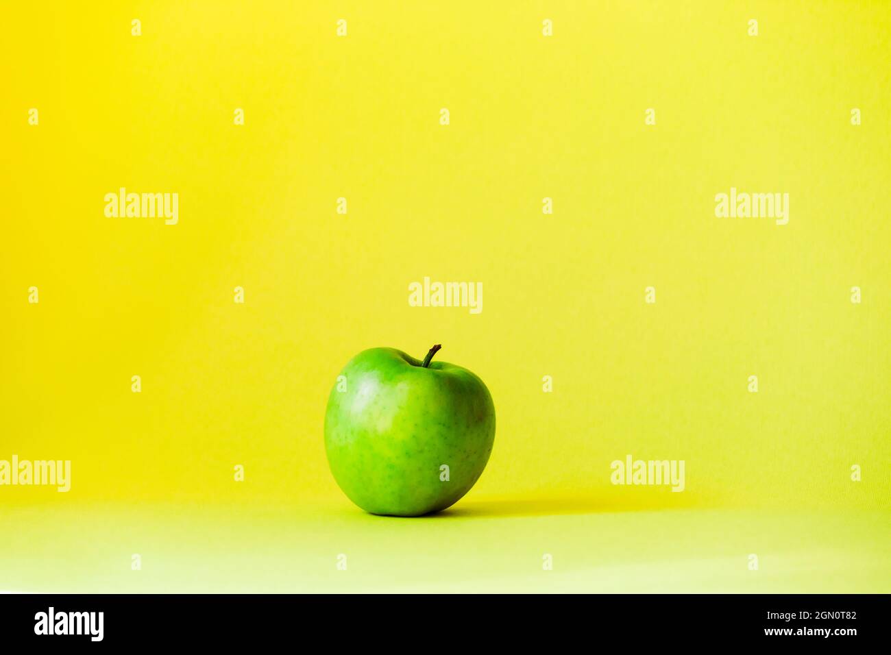 La pomme verte se trouve au milieu sur un fond jaune vif. Banque D'Images