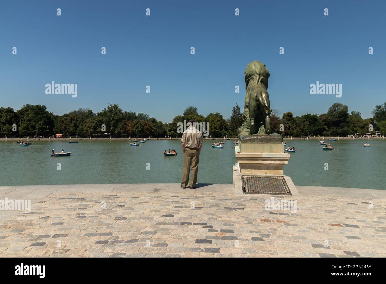 Photo d'un homme adulte se tenant près d'une statue de lion dans le parc El Retiro à Madrid, Espagne Banque D'Images