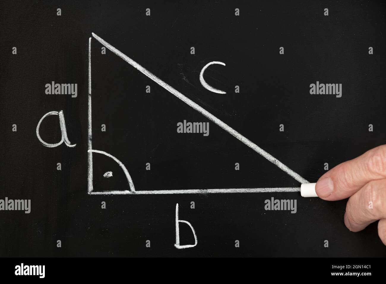 Un enseignant écrit l'équation du théorème pythagore sur un tableau noir tout en enseignant un groupe d'élèves dans une salle de classe. Banque D'Images