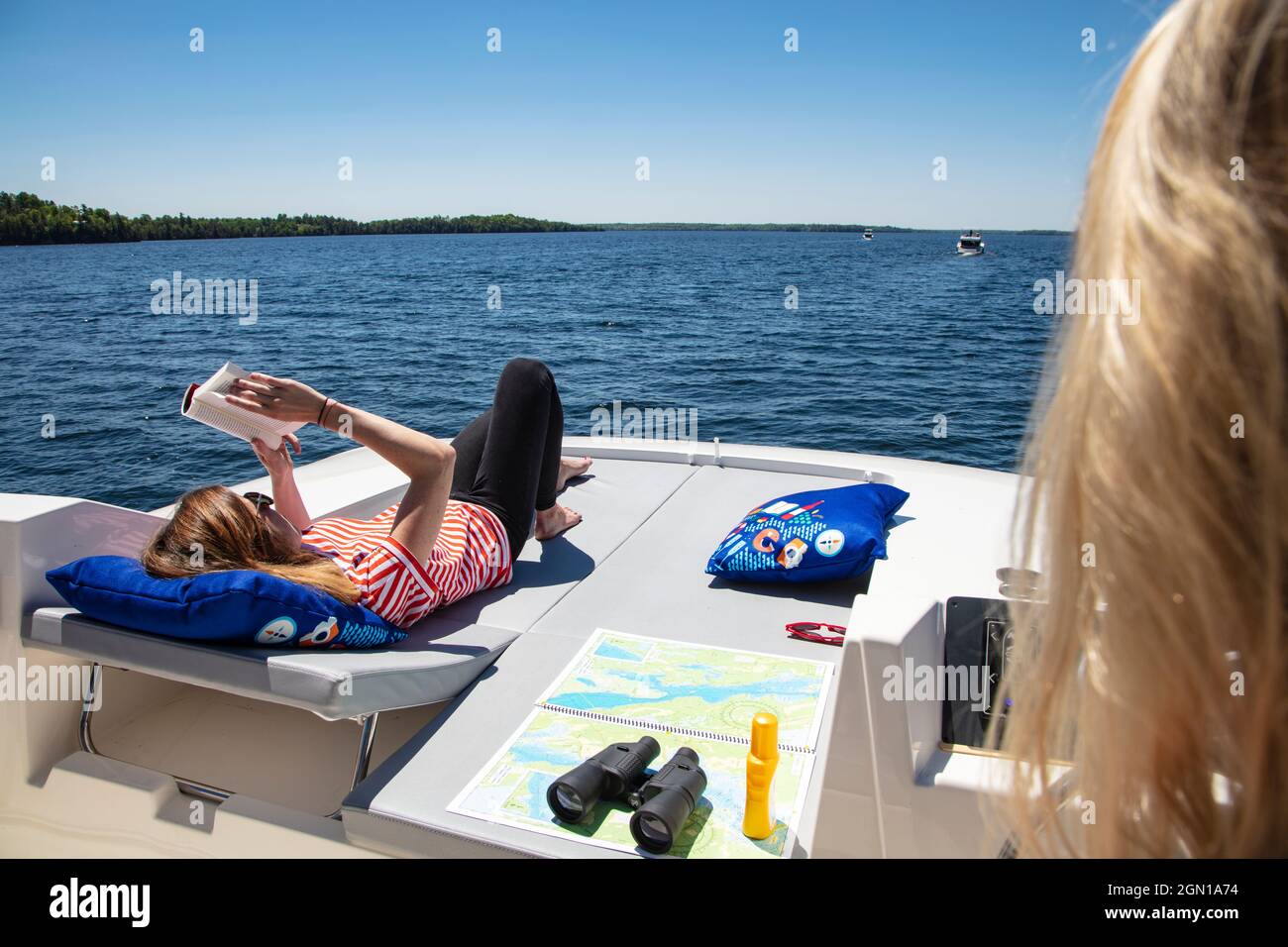 Une jeune femme se détend sur la terrasse d'une péniche le Boat Horizon et lit un livre, Lower Rideau Lake, Ontario, Canada, Amérique du Nord Banque D'Images