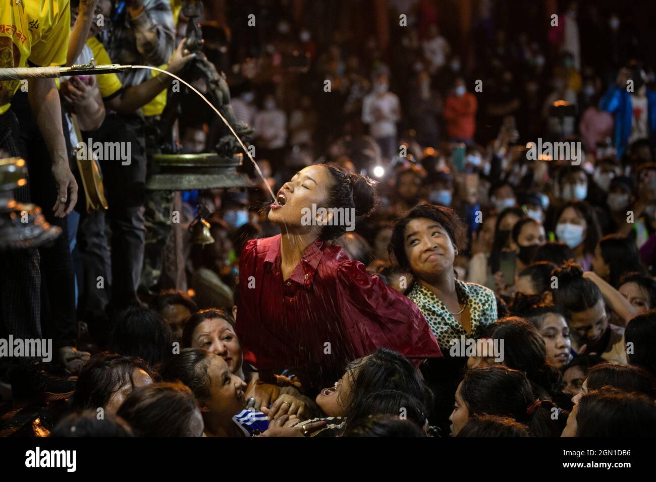 Katmandou, Népal. 21 septembre 2021. Les femmes népalaises luttent pour boire de l'alcool maison de la bouche de Deity Swet Bhairav comme des bénédictions pendant le festival Indra Jatra.le festival annuel, nommé d'après Indra, le dieu de la pluie et du ciel, est célébré par le culte, la joie, le chant, la danse et la fête dans la vallée de Katmandou pour marquer la fin de la saison de la mousson. Indra, la déesse vivante Kumari et d'autres divinités sont adorés pendant le festival. Crédit : SOPA Images Limited/Alamy Live News Banque D'Images