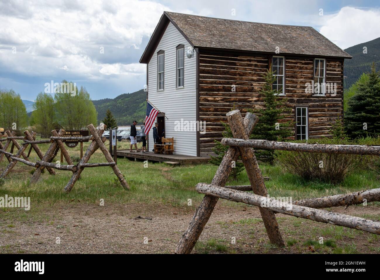 Les touristes entrent dans le centre d'accueil de Twin Lakes, Colorado, entouré d'une clôture en rondins et d'herbe verte, les montagnes Rocheuses en arrière-plan. Banque D'Images