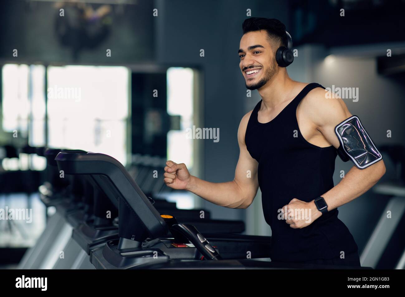 Un homme arabe musclé dans un casque sans fil jogging sur un tapis roulant  à la salle de gym Photo Stock - Alamy