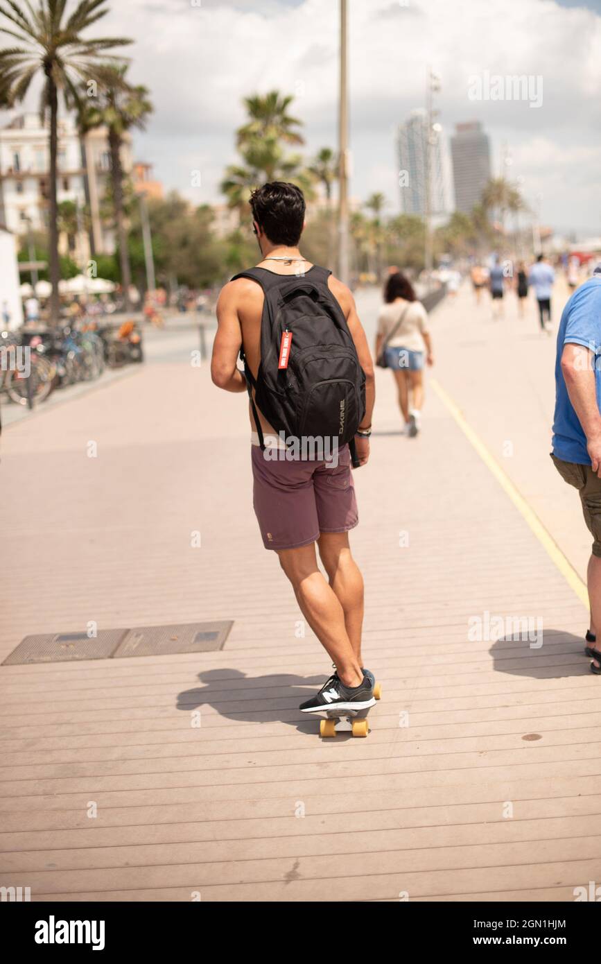 BARCELONE, ESPAGNE - 04 septembre 2021 : un homme sans chemise sur sa  planche à roulettes sur la plage avec un sac à dos sur son dos Photo Stock  - Alamy