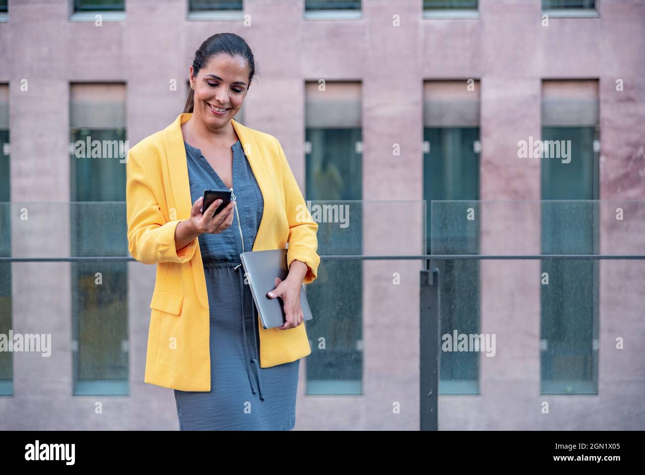 Femme d'affaires caucasienne avec téléphone mobile et ordinateur à l'extérieur. Banque D'Images