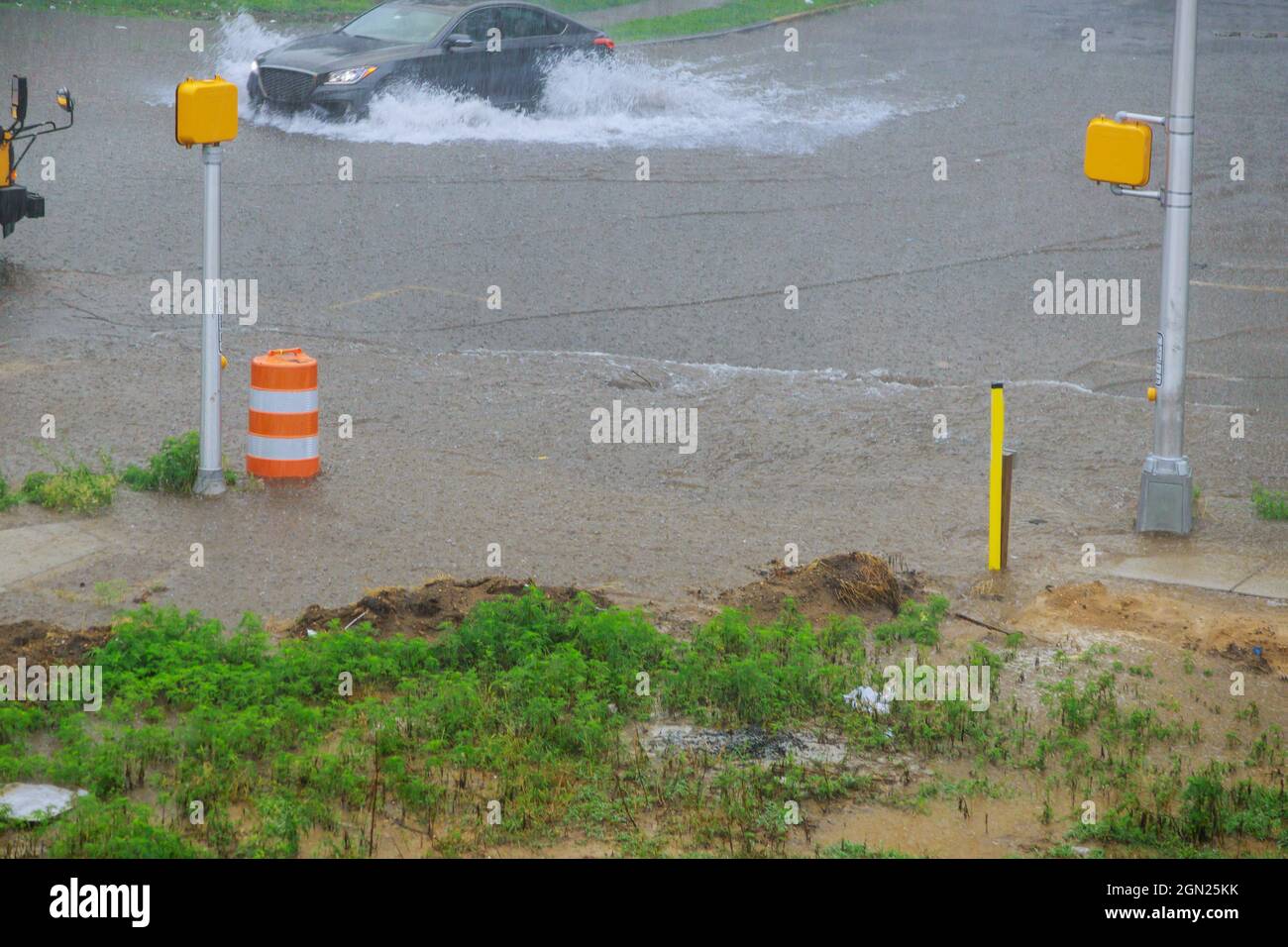 Une voiture qui traverse rapidement une grande flaque de sol qui envahissent la route lors d'une grande éclaboussure d'eau Banque D'Images