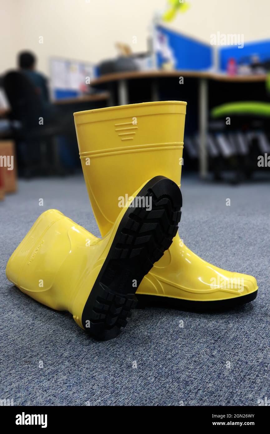 Une paire de bottes jaunes en caoutchouc utilisées par les travailleurs, pour le jardinage et toutes les activités dans les endroits humides pour protéger les pieds de la saleté et des produits chimiques nocifs Banque D'Images