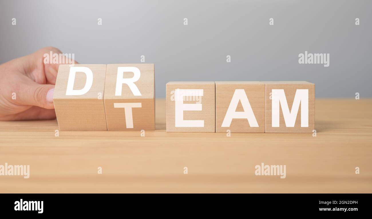 Dream team sur des cubes en bois. La main tourne un dé et change le mot rêve à l'équipe. Message Dream Team. Concept d'entreprise et d'équipe de rêve, espace de copie Banque D'Images