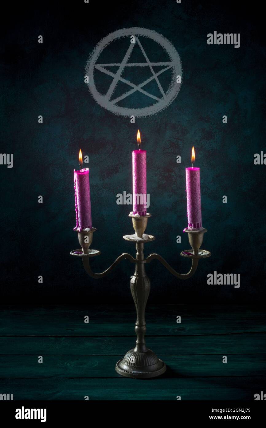 Bougie magique. Bougies violettes dans un chandelier vintage avec un  pentagramme sur un fond sombre Photo Stock - Alamy