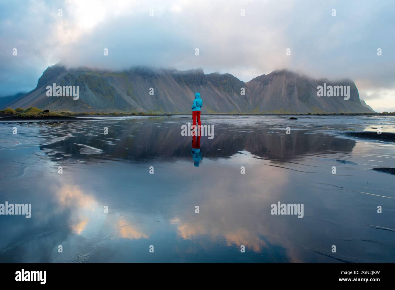 Paysage islandais, reflet d'une femme treking et de la montagne Vestrahorn dans les eaux de l'océan Atlantique. Péninsule de Stokksnes, Hofn, Icel Banque D'Images