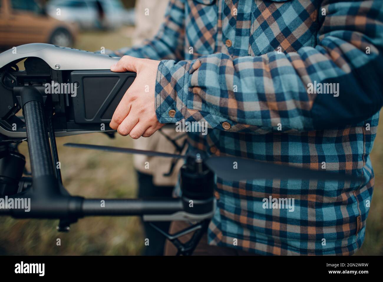 Homme pilote vérifiant le remplacement et la charge de la batterie du drone quadcopter avant le vol aérien et le tournage Banque D'Images