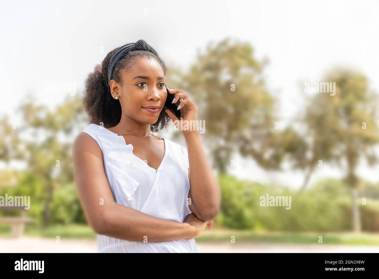 Une jeune femme afro-américaine parle avec son téléphone dans le parc Banque D'Images