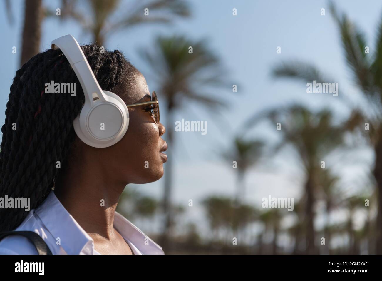 Une jeune femme écoute de la musique à l'aide d'un casque sans fil en plein air Banque D'Images