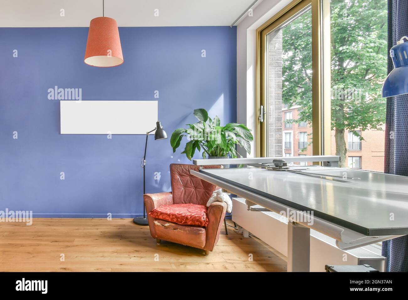 Intérieur de la chambre avec table d'ingénierie et fauteuil à l'ancienne près de la plante en pot et de la fenêtre Banque D'Images