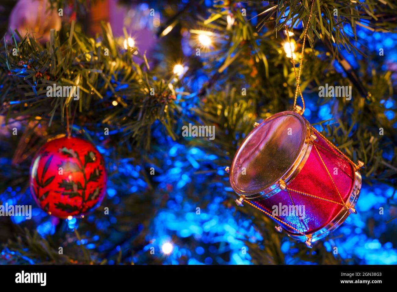 Jouets décoratifs en forme de tambour suspendus sur des branches de conifères arbre de Noël avec guirlande brillante Banque D'Images