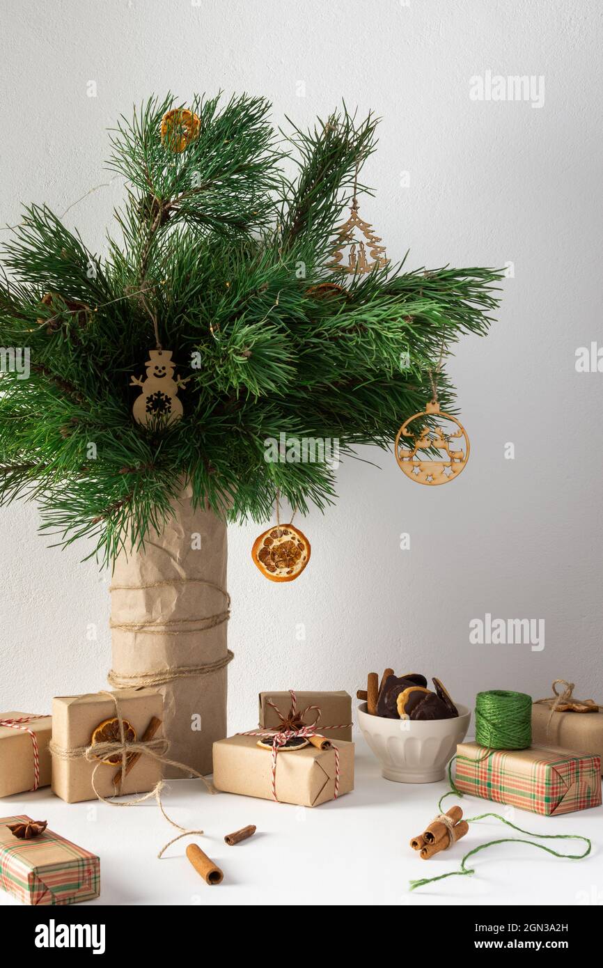 Table de noël festive, vase avec branches et jouets en pin, boîtes-cadeaux et une assiette de biscuits au chocolat, agrumes séchés, cannelle avec anis étoilé Banque D'Images