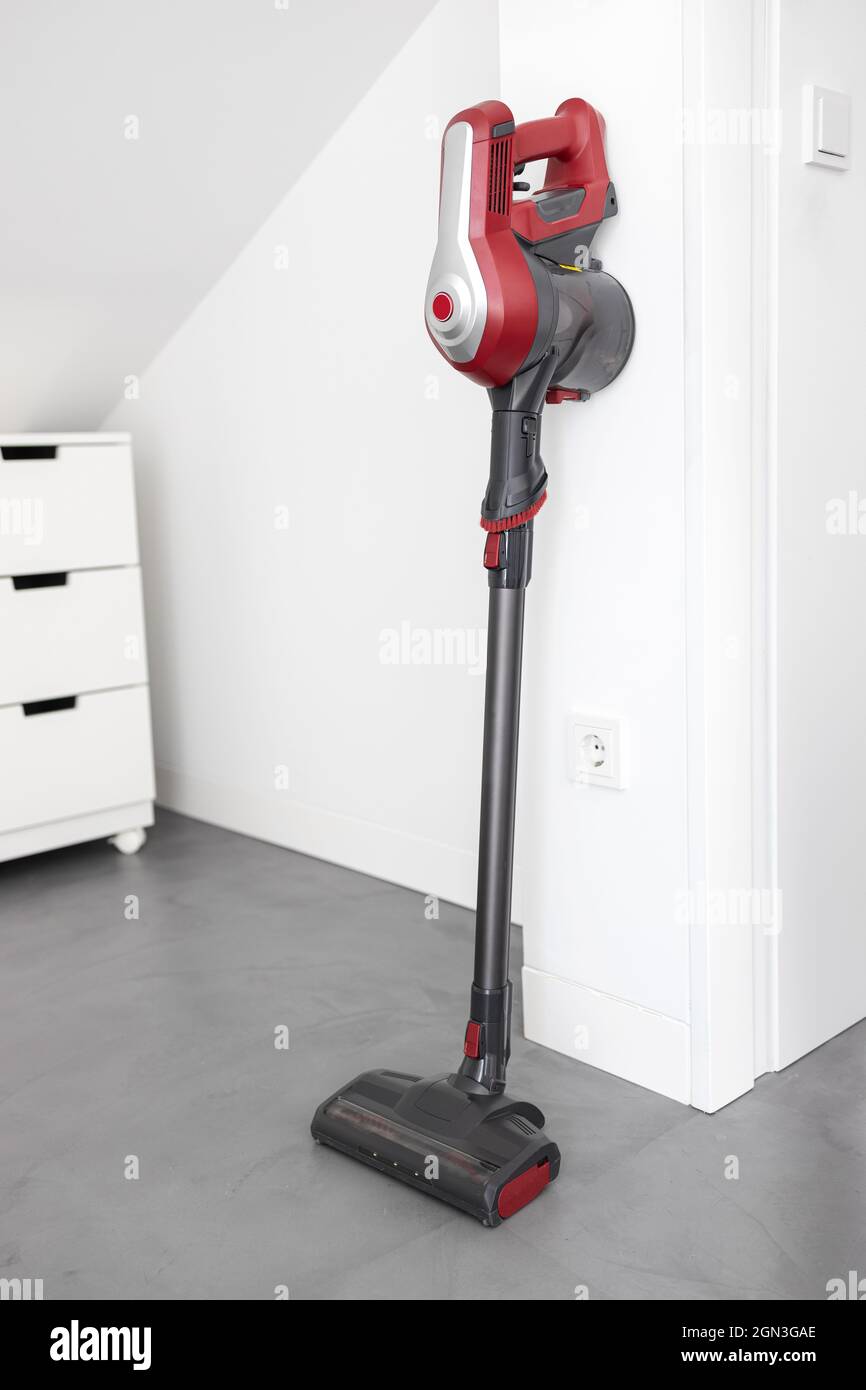 Aspirateur sans fil moderne appuyé sur un mur d'une pièce. Concept de devoir Banque D'Images