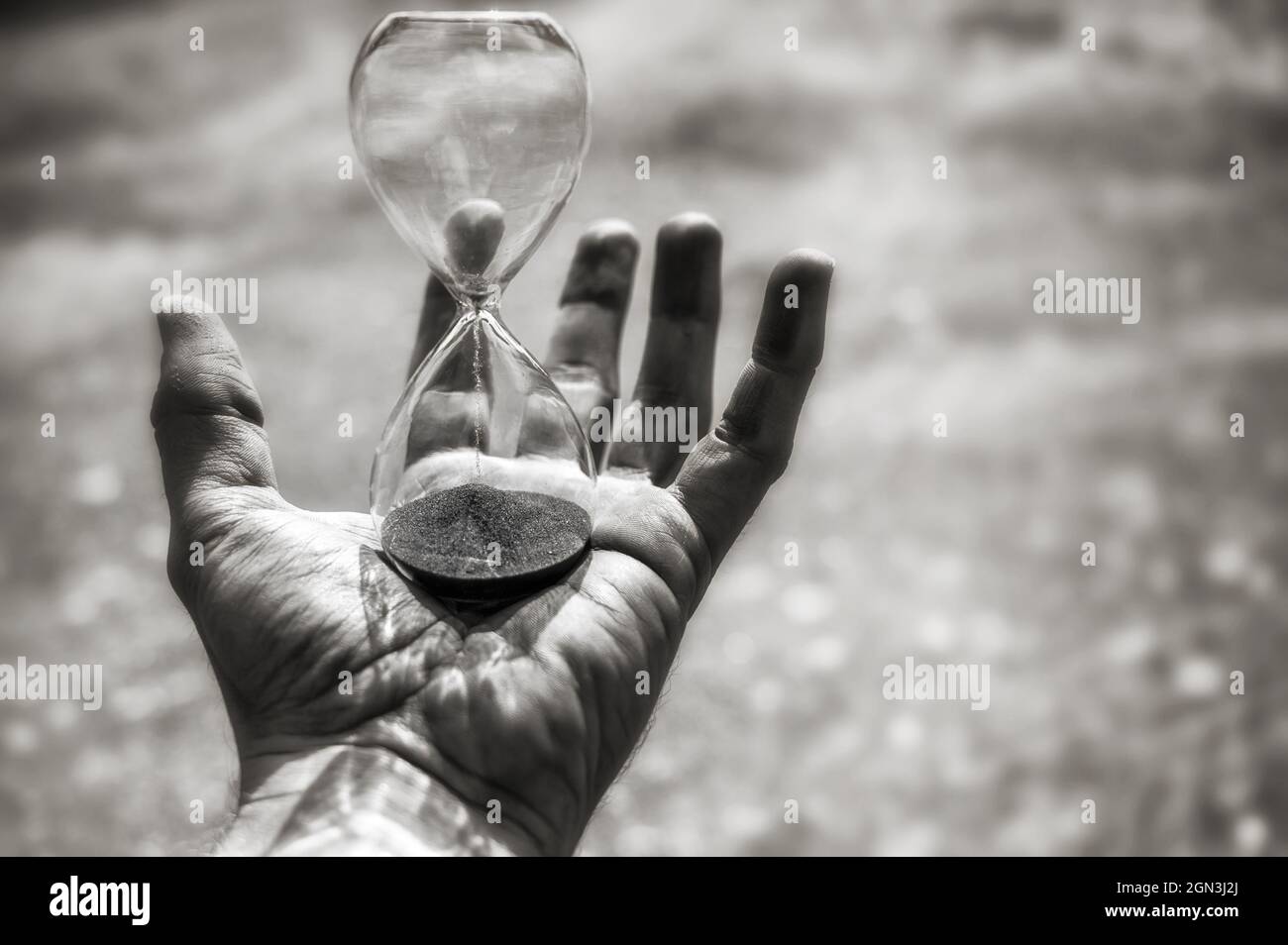 HourGlass dans la main d'un homme froissé comme symbole du temps de passage Banque D'Images