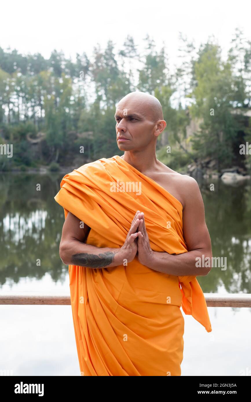 moine bouddhiste dans une robe traditionnelle qui donne loin tout en  méditant près du lac dans la forêt Photo Stock - Alamy