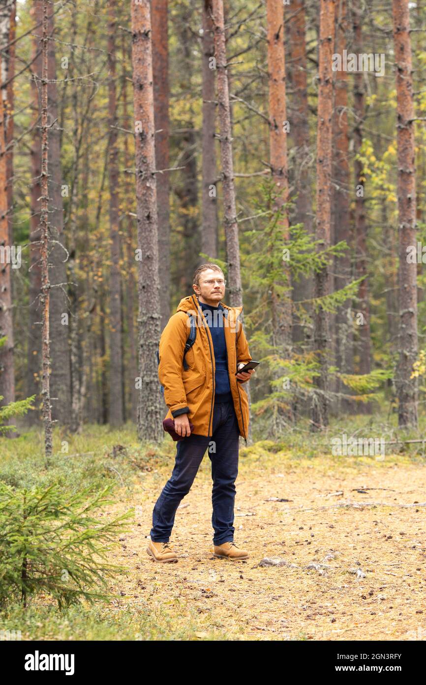 Portrait d'un homme du Caucase avec un smartphone dans sa main. Un homme est à la recherche de sa position dans la forêt - image Banque D'Images