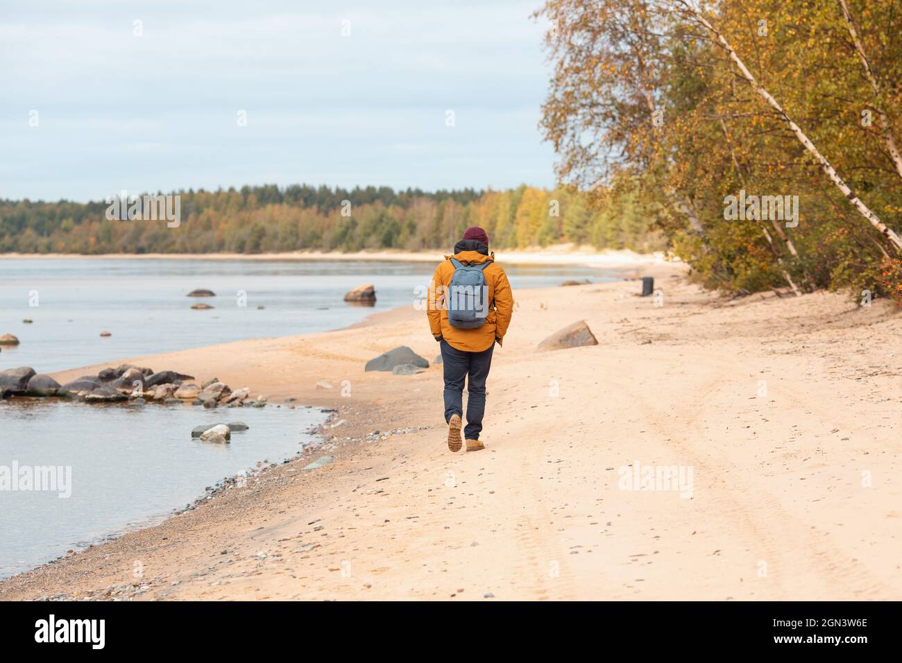 Vue arrière de l'homme en veste jaune marchant le long du lac - image Banque D'Images