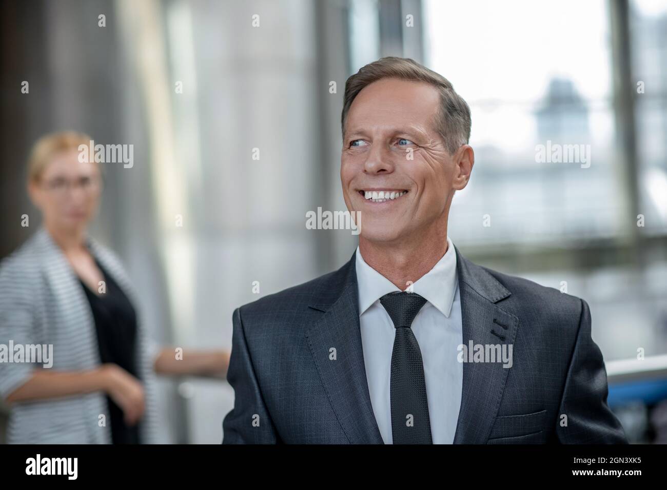 Homme adulte avec un sourire éclatant debout à l'aéroport Banque D'Images