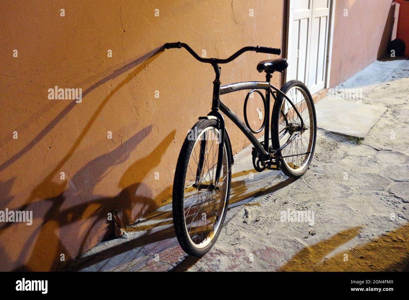 Un vélo sur une rue traversant au crépuscule. L'incidence de la lumière et de l'ombre sur un compagnon à tout moment, pour toutes les destinations Banque D'Images