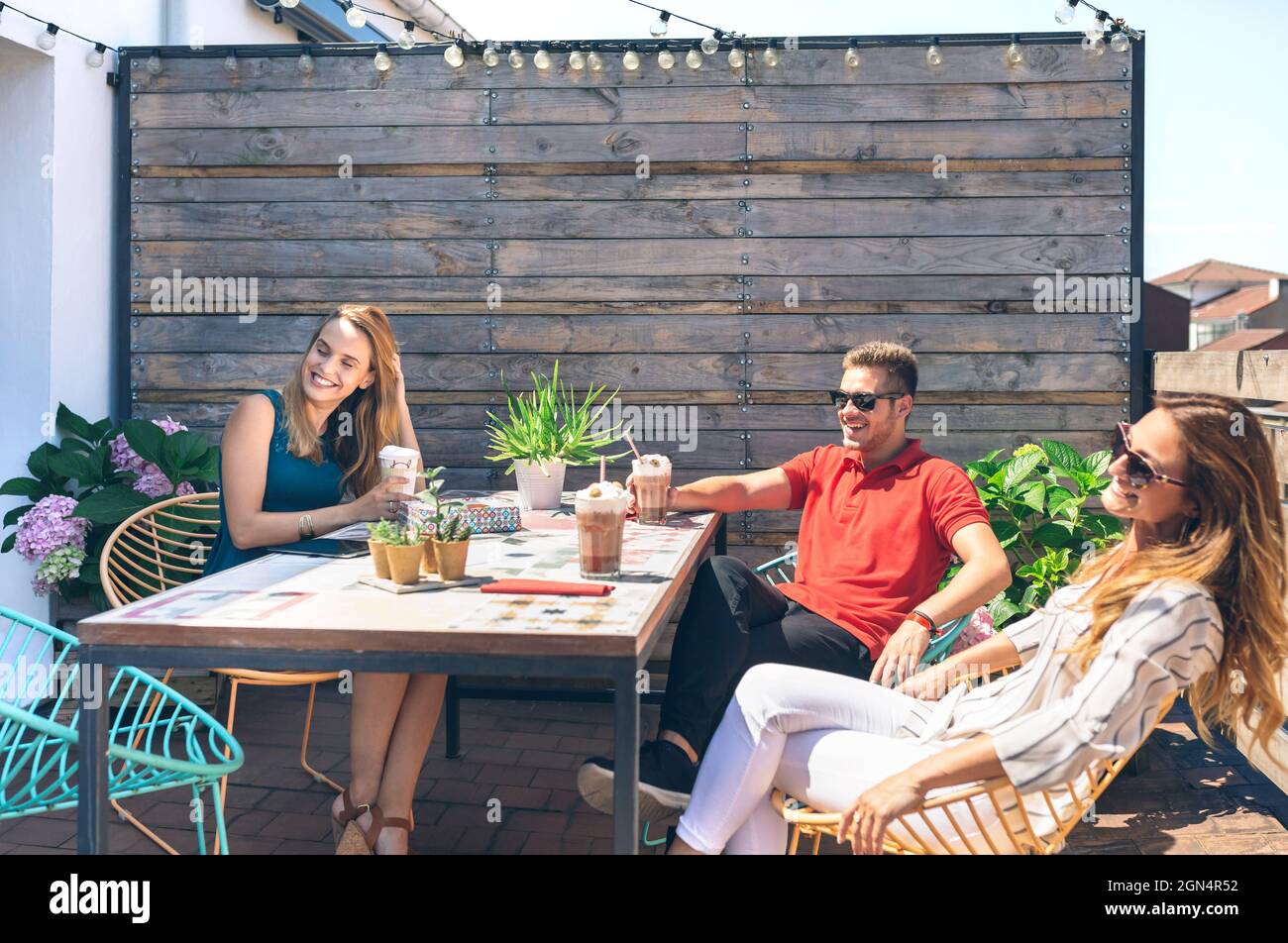 Personnes assises en train de boire un verre en terrasseen souriant et ...