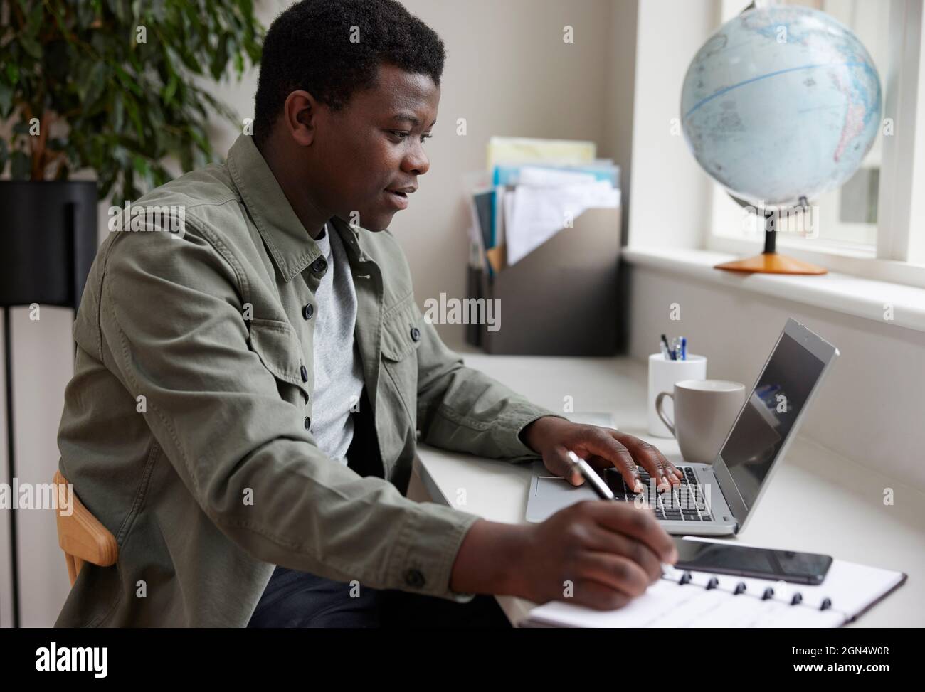 Jeune homme enthousiaste travaillant à domicile sur ordinateur portable Banque D'Images