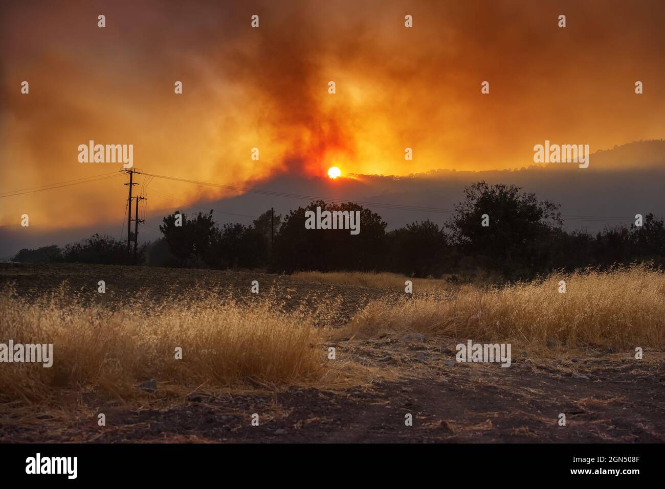 Paysage rural de Chypre au coucher du soleil avec champ agricole et feu de forêt dramatique sur fond Banque D'Images