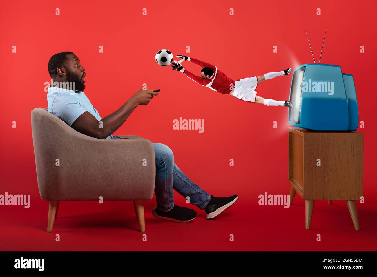 Gardien de but de football sautant hors de la télévision pendant qu'un spectateur regarde un match Banque D'Images