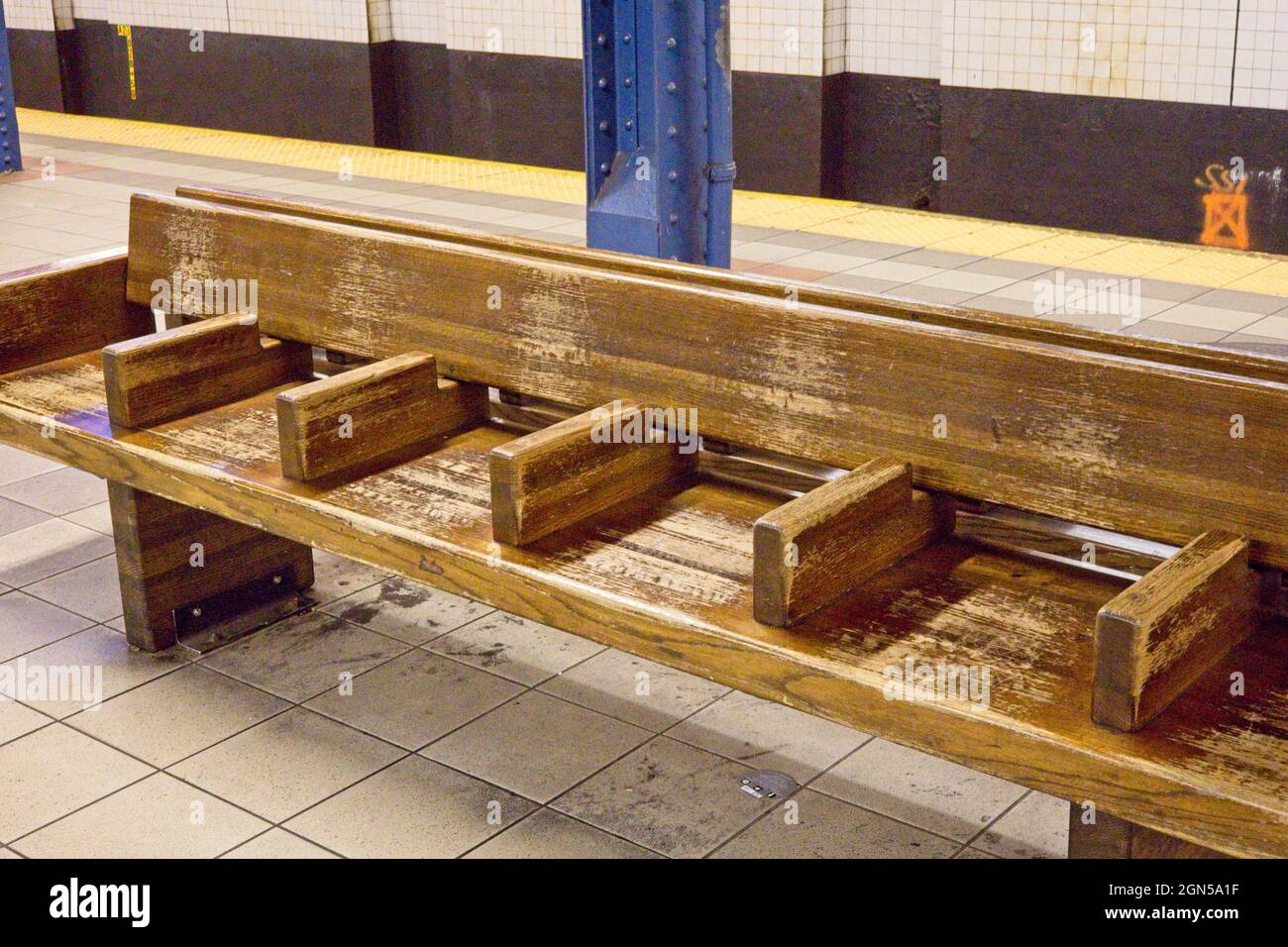 New York, NY, USA - 22 septembre 2021: Banc en bois sur plate-forme de métro avec séparateurs individuels pour empêcher de dormir sur la longueur du banc Banque D'Images