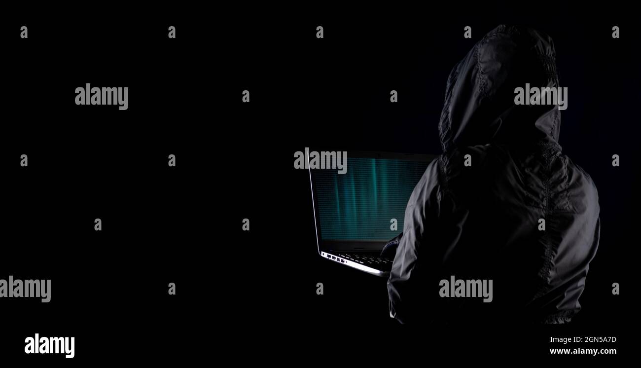 Hacker cybercriminel à capuchon utilisant un ordinateur portable pour pirater Internet dans le cyberespace mais fond noir, concept de sécurité des données personnelles sur Internet Banque D'Images
