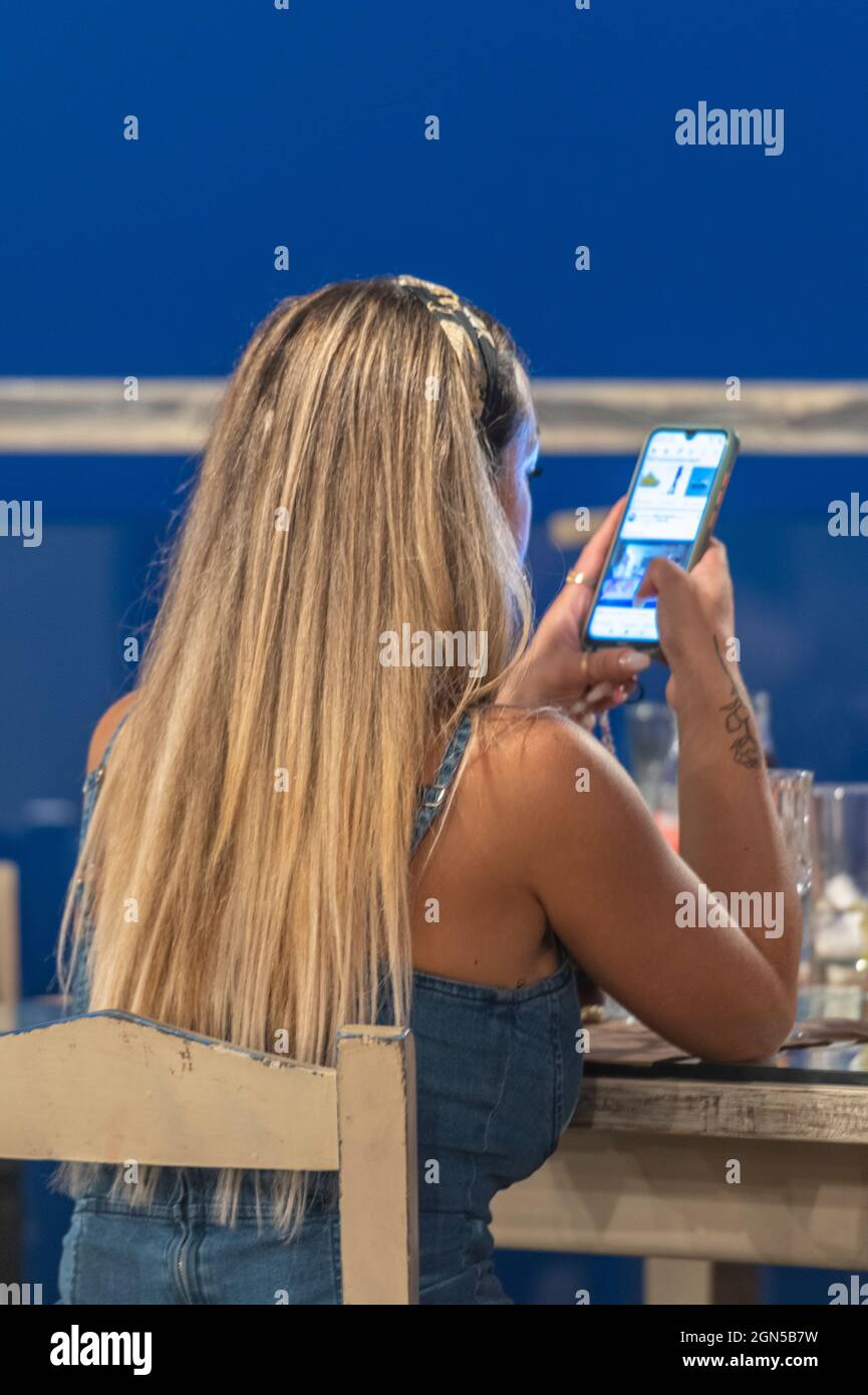 Jeune femme attrayante utilisant un smartphone, femme utilisant un téléphone mobile, longue blonde cheveux jeune femme SMS, femme utilisant les médias sociaux au téléphone. Banque D'Images