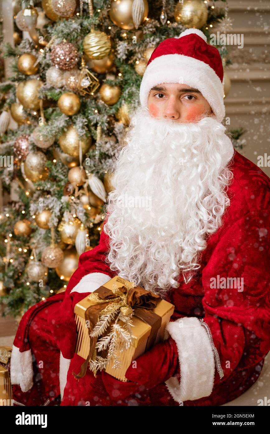 Le Père Noël tient un cadeau dans des moufles sur un arbre de Noël,  ambiance festive Photo Stock - Alamy