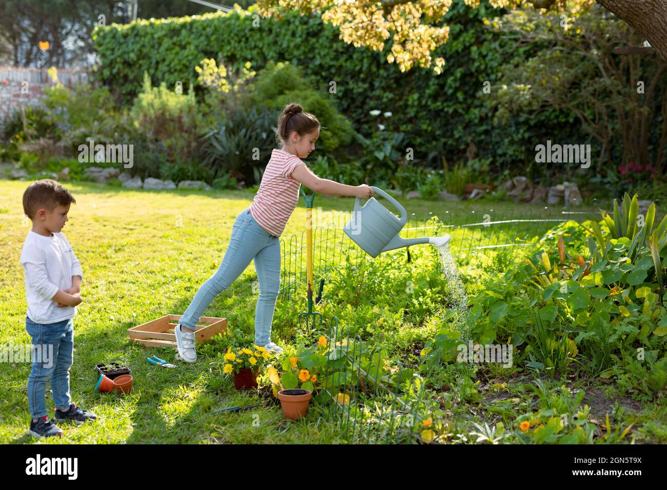 Bonne sœur caucasienne et frère arrosoir les plantes ensemble Banque D'Images