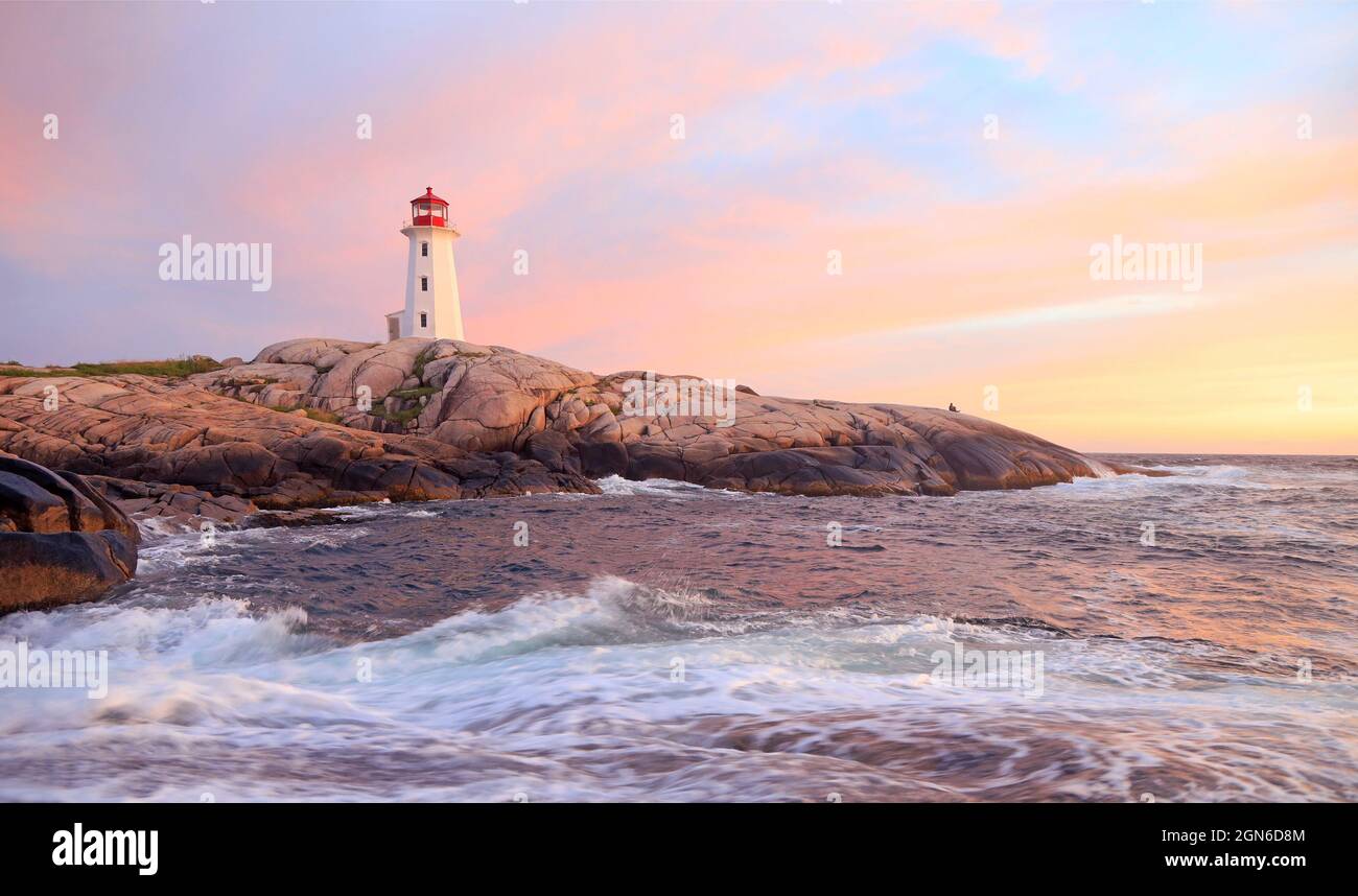 Peggy’s Cove Lighthouse illuminé au coucher du soleil avec un ciel et des vagues violettes spectaculaires, Nouvelle-Écosse, Canada Banque D'Images