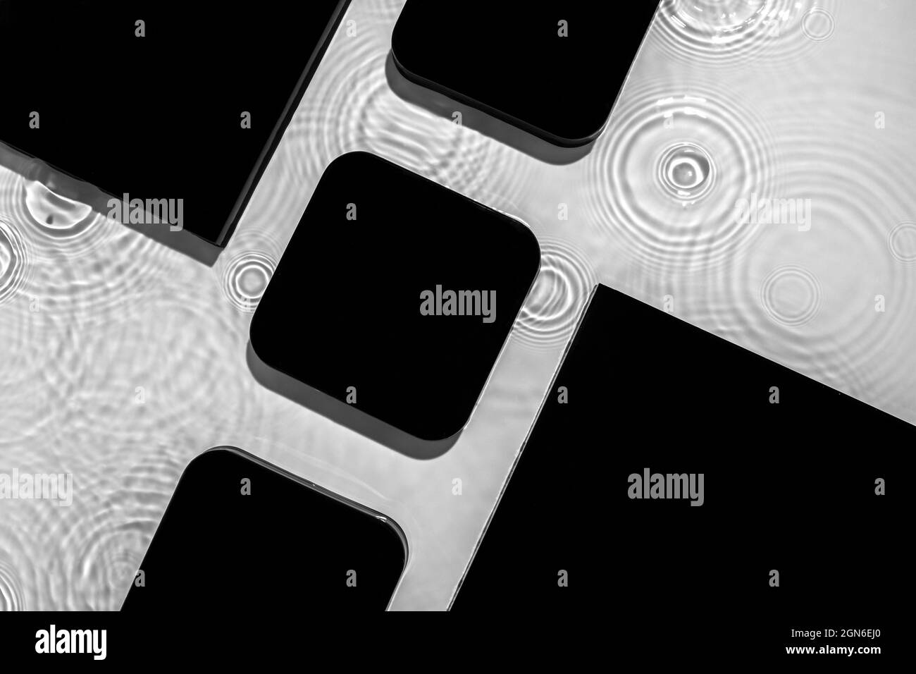 Composition de figurines géométriques noires abstraites sur de l'eau transparente Banque D'Images