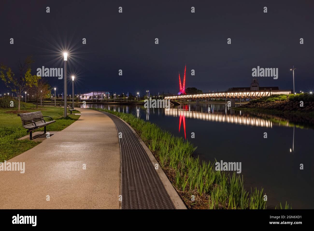 Oklahoma City, Oklahoma, Etats-Unis - 15 avril 2021 : le Scissortail Park de nuit, avec la rivière artificielle et la sculpture abstraite en arrière-plan Banque D'Images