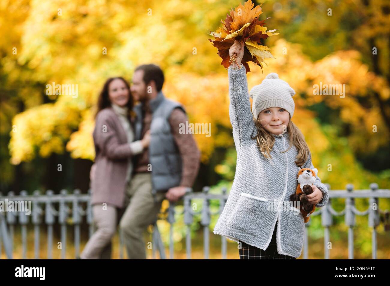 Promenade en famille dans le parc d'automne. Les parents amoureux de petite fille embrassent dehors dans la forêt avec des arbres colorés Banque D'Images