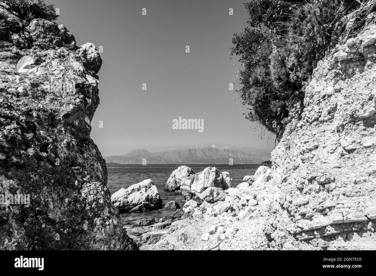 Rochers blancs sur la plage de galets sur la côte de l'île en Grèce. Été nature sauvage voyage à la mer Ionienne. Noir et blanc Banque D'Images