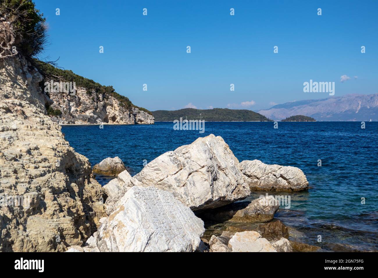 Falaises côtières et grands rochers de marbre blanc dans l'eau claire bleue avec des montagnes et ciel clair à l'horizon. L'île de Lefkada en Grèce. Été nature vive tra Banque D'Images