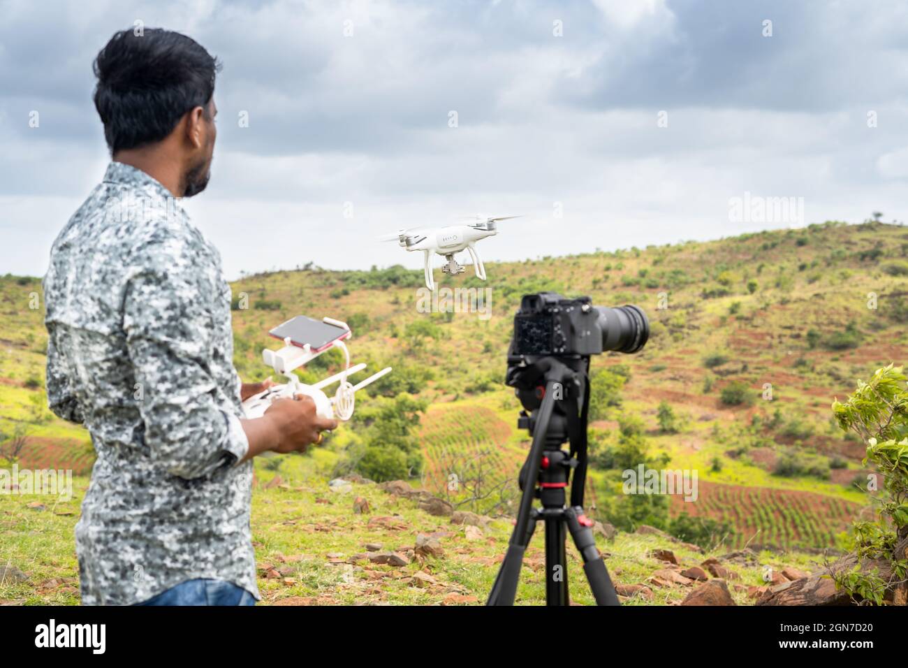 Focus sur drone, jeune vidéaste filmant la vidéo en contrôlant drone à l'aide de la télécommande - concept de photographie de drone professionnelle et aérienne Banque D'Images