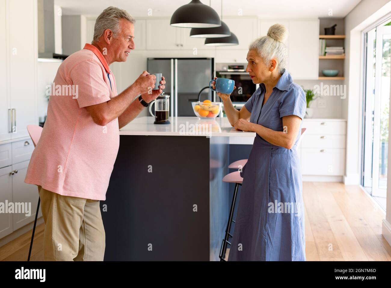 Un couple de personnes âgées caucasiennes boit du café ensemble et parle dans la cuisine Banque D'Images