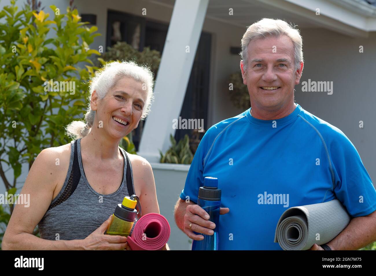 Joyeux couple caucasien senior tenant des tapis de yoga et regardant la caméra Banque D'Images