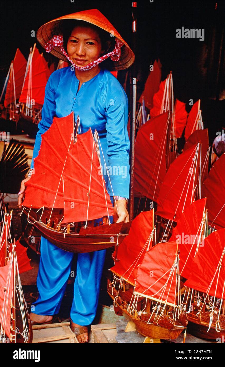 Vietnam. Ho Chi Minh ville. Femme locale dans la boutique de souvenirs artisanaux vendant des junks chinois modèles. Banque D'Images