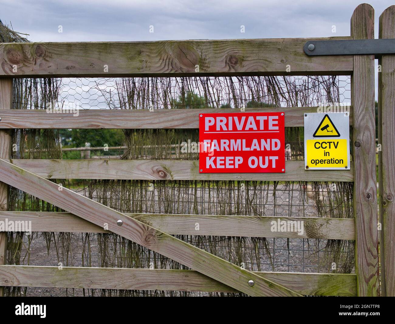 Des panneaux sur une porte de ferme en bois avertissent que la zone est une terre agricole privée et que l'entrée est interdite. Un panneau jaune indique que la sécurité CCTV est en cours d'utilisation. Banque D'Images