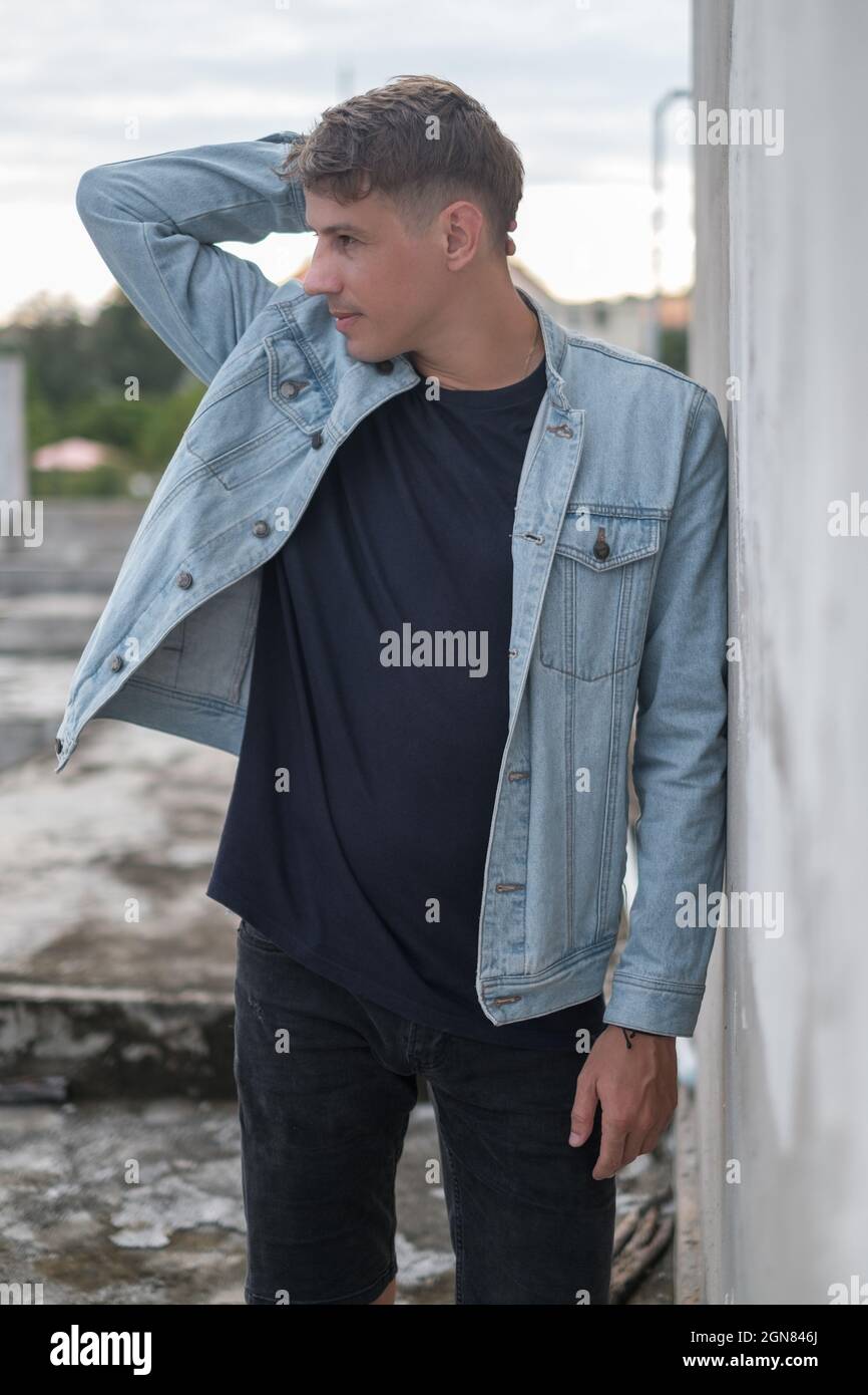 Portrait d'un jeune homme caucasien élégant en veste décontractée et en denim, en regardant de côté. Tenant sa tête avec sa main, regard pensif. Haute qualité Banque D'Images