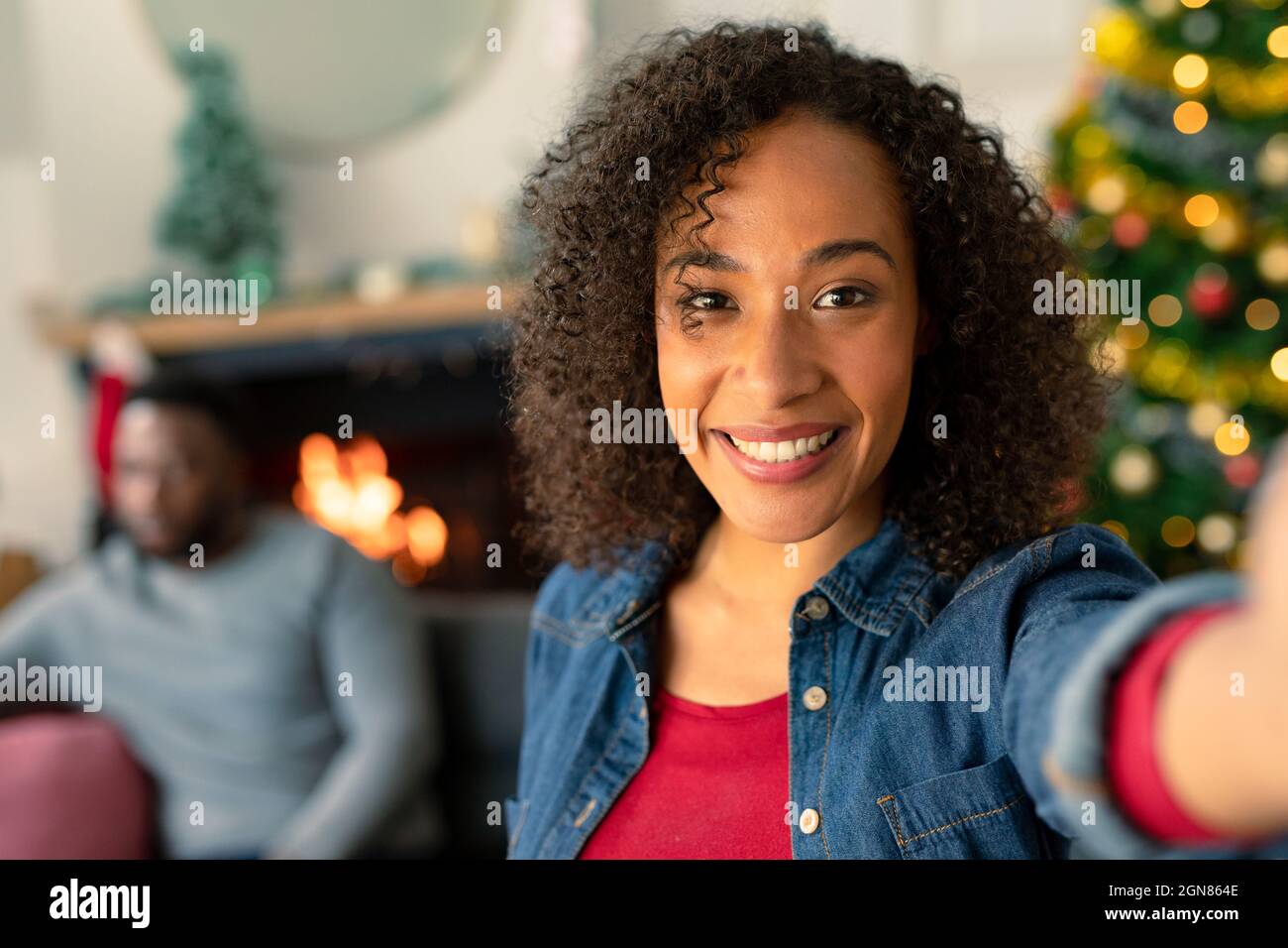 Bonne femme afro-américaine qui prend le selfie, décorations de noël en arrière-plan, Noël et fête à la maison. Banque D'Images
