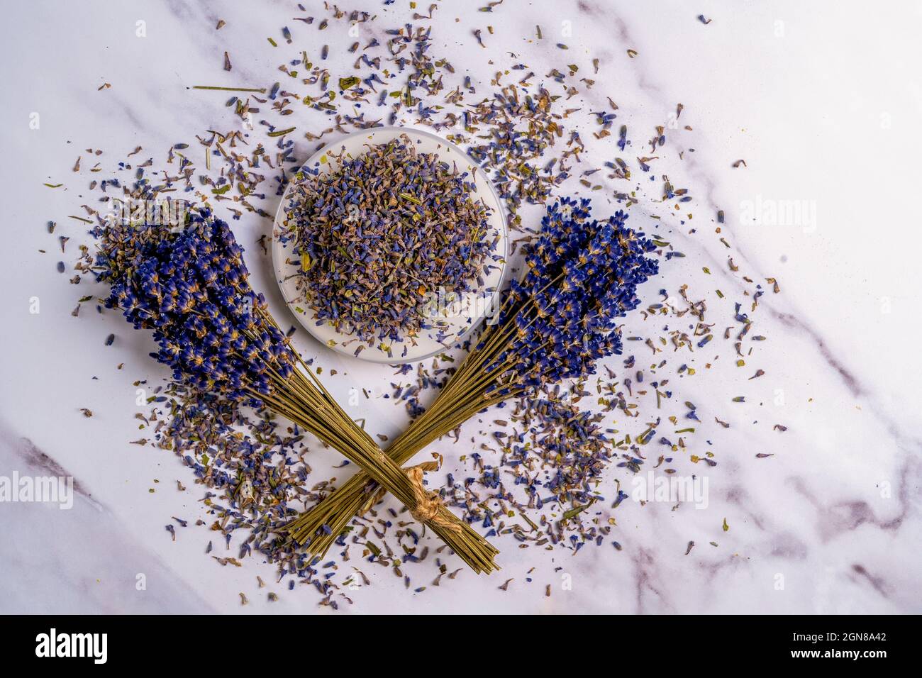 Encore la vie Aromatherapy séché pains de lavande, fleurs et pétales dispersés et étamines sur un plat sur un fond de marbre Banque D'Images